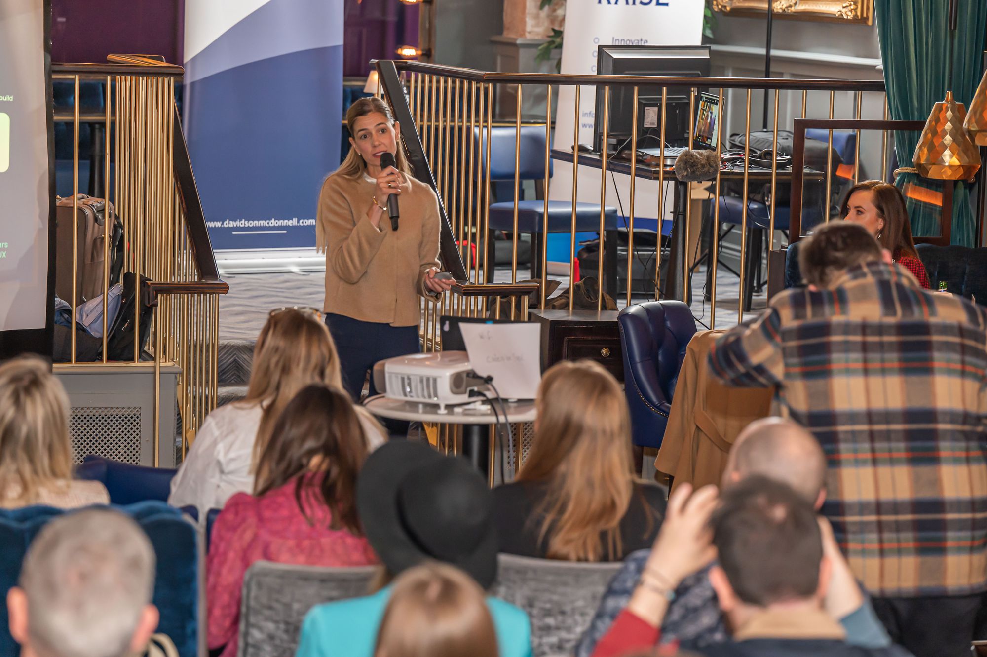 A female pitching for investment in a bar full of attendees