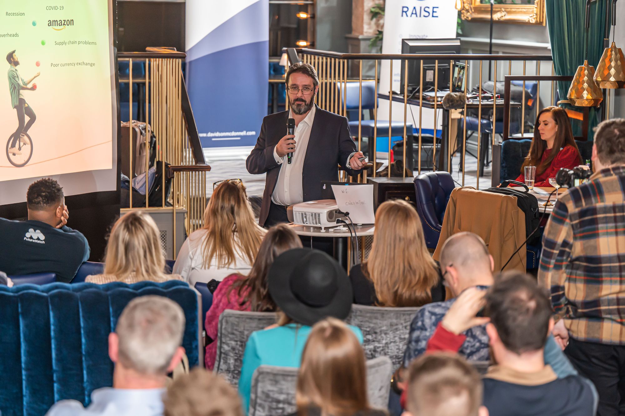 A male pitching for investment in front of a large crowd in a restaurant