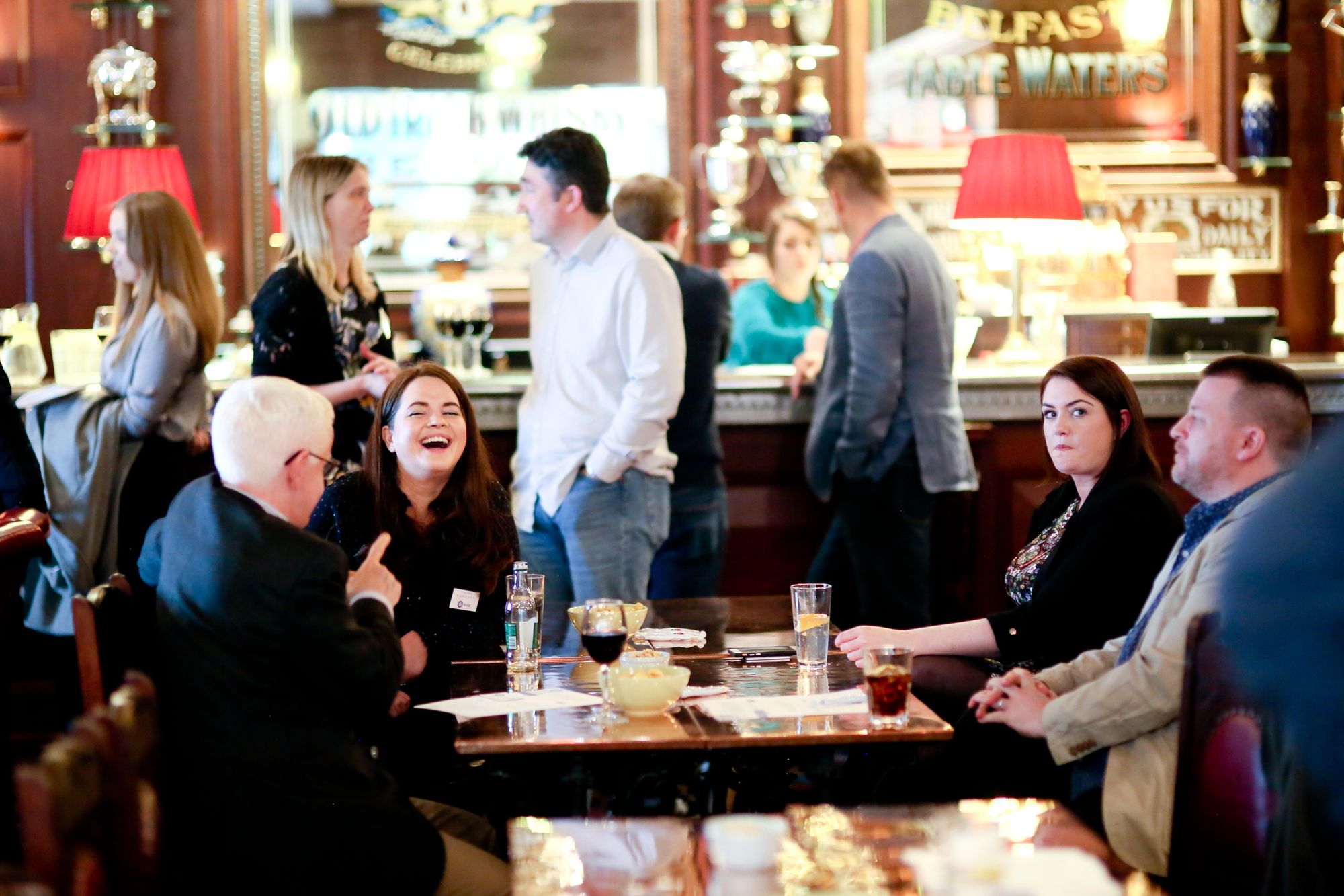 A group of people around a table in a bar laughing