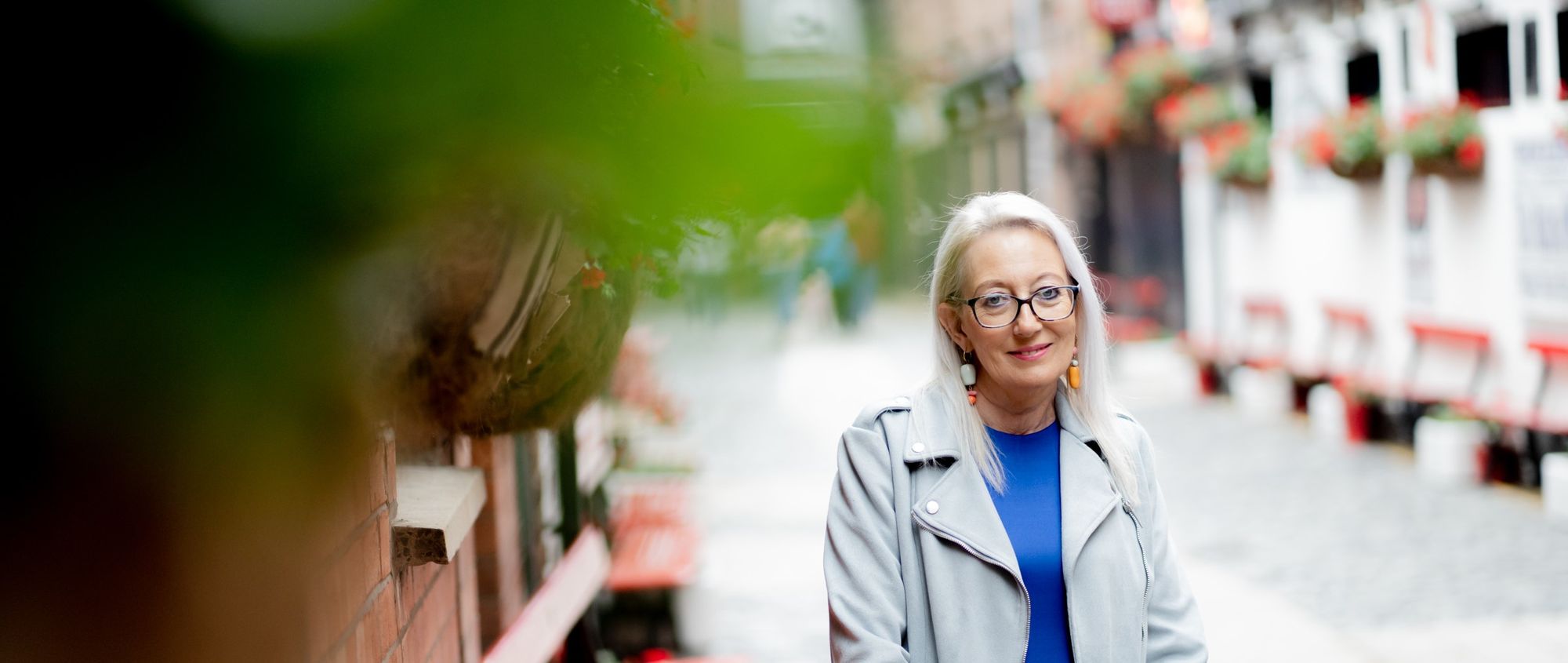 A lady in a well lit, decorative Belfast alleyway